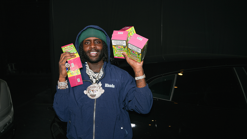 CHIEF KEEF holding multiple boxes of CHIEF KEEF GROSS MYSTERY Loose Leaf in a dark setting