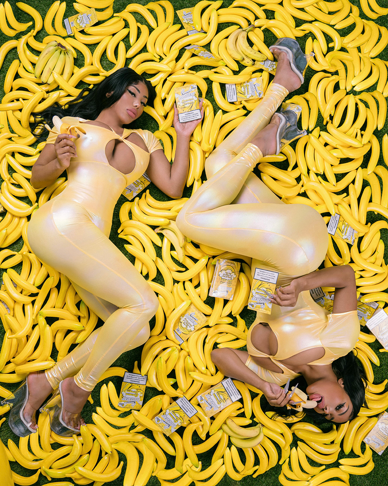 The Clermont Twins in yellow outfits sitting on a banana-shaped couch with 'Loose Leaf' BANANA DREAM 