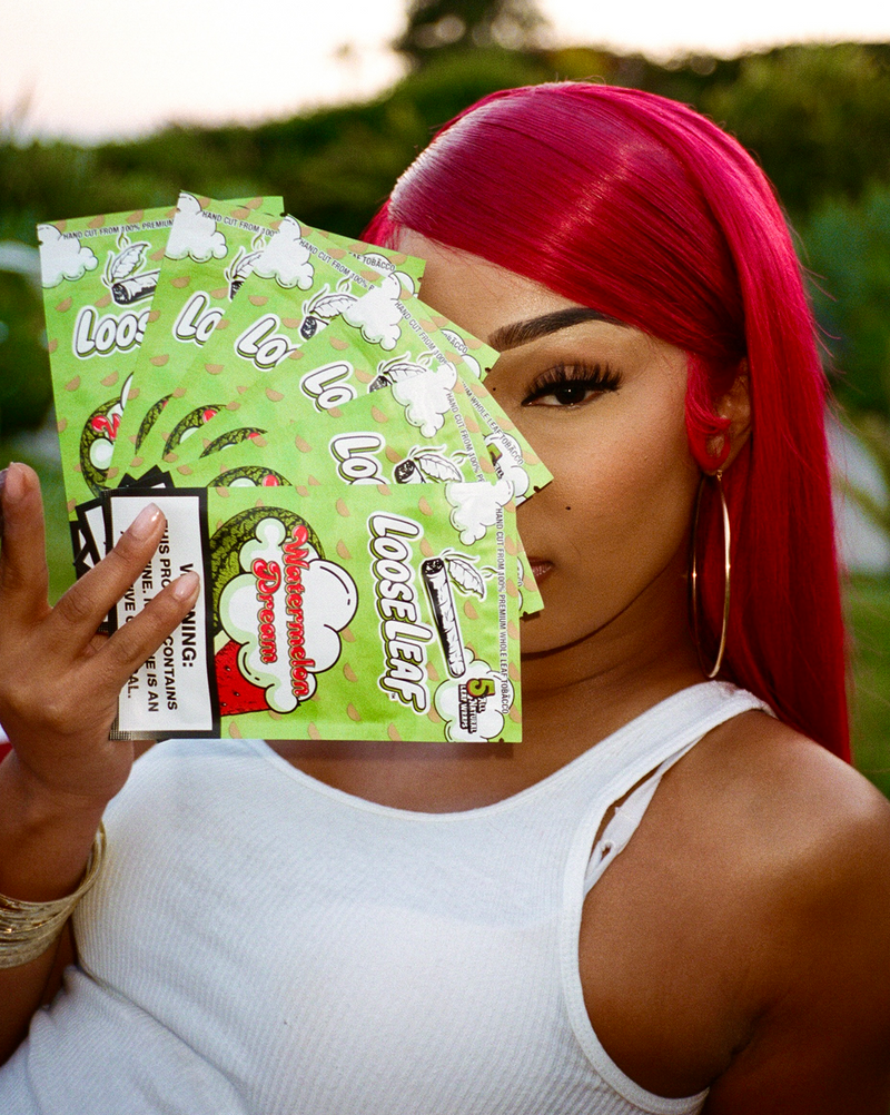 RUBI ROSE with red hair holding Watermelon Dream Loose Leaf, surrounded by watermelons.