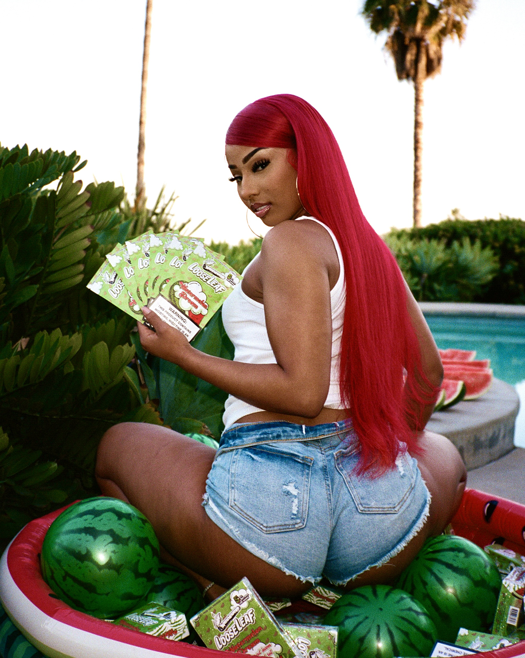 RUBI ROSE with red hair lying on watermelon holding Watermelon Dream Loose Leaf, surrounded by watermelons.